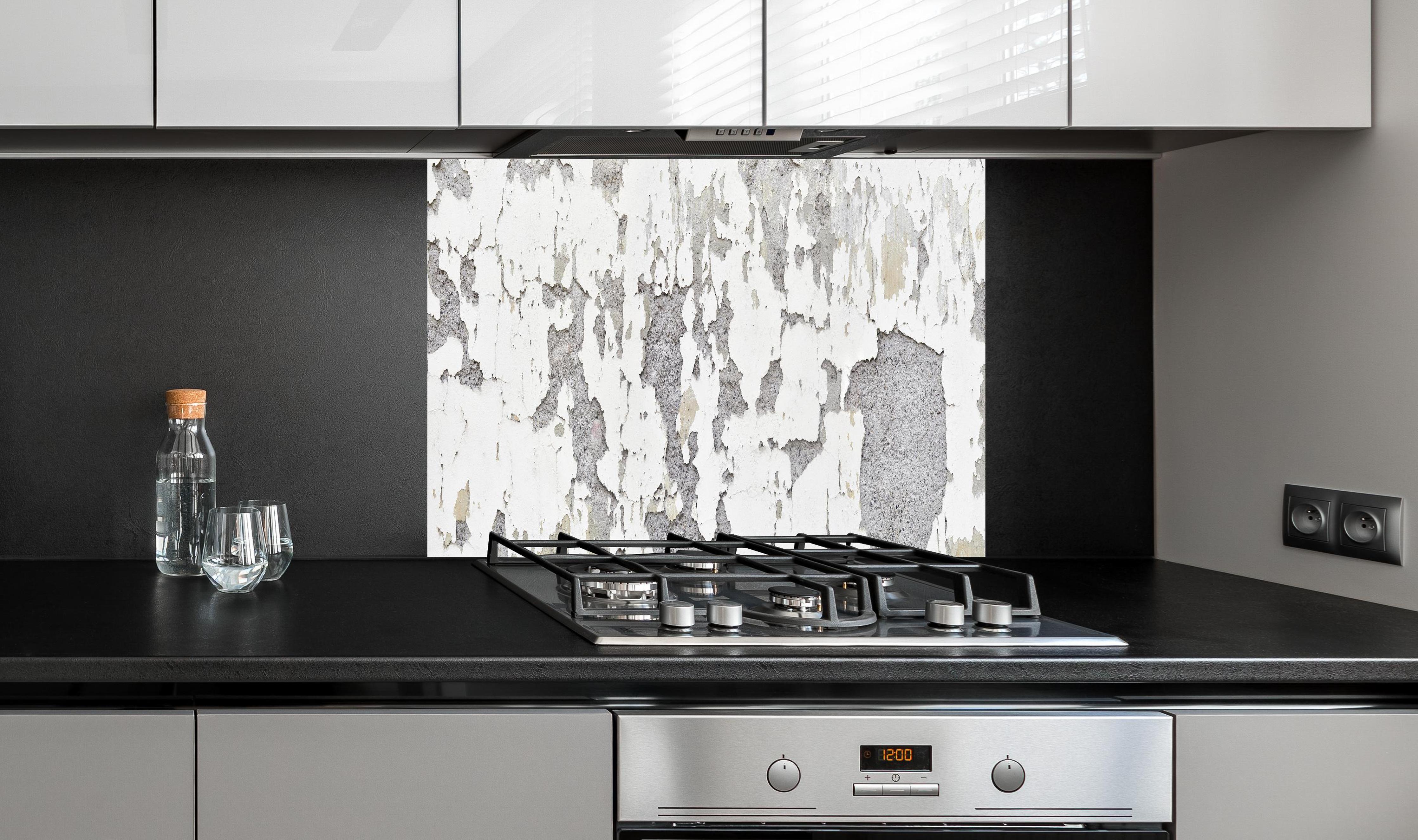 Spritzschutz - Zerplatze Fassade eines alten Hauses hinter einem Cerankochfeld zwischen Holz-Kochutensilien
