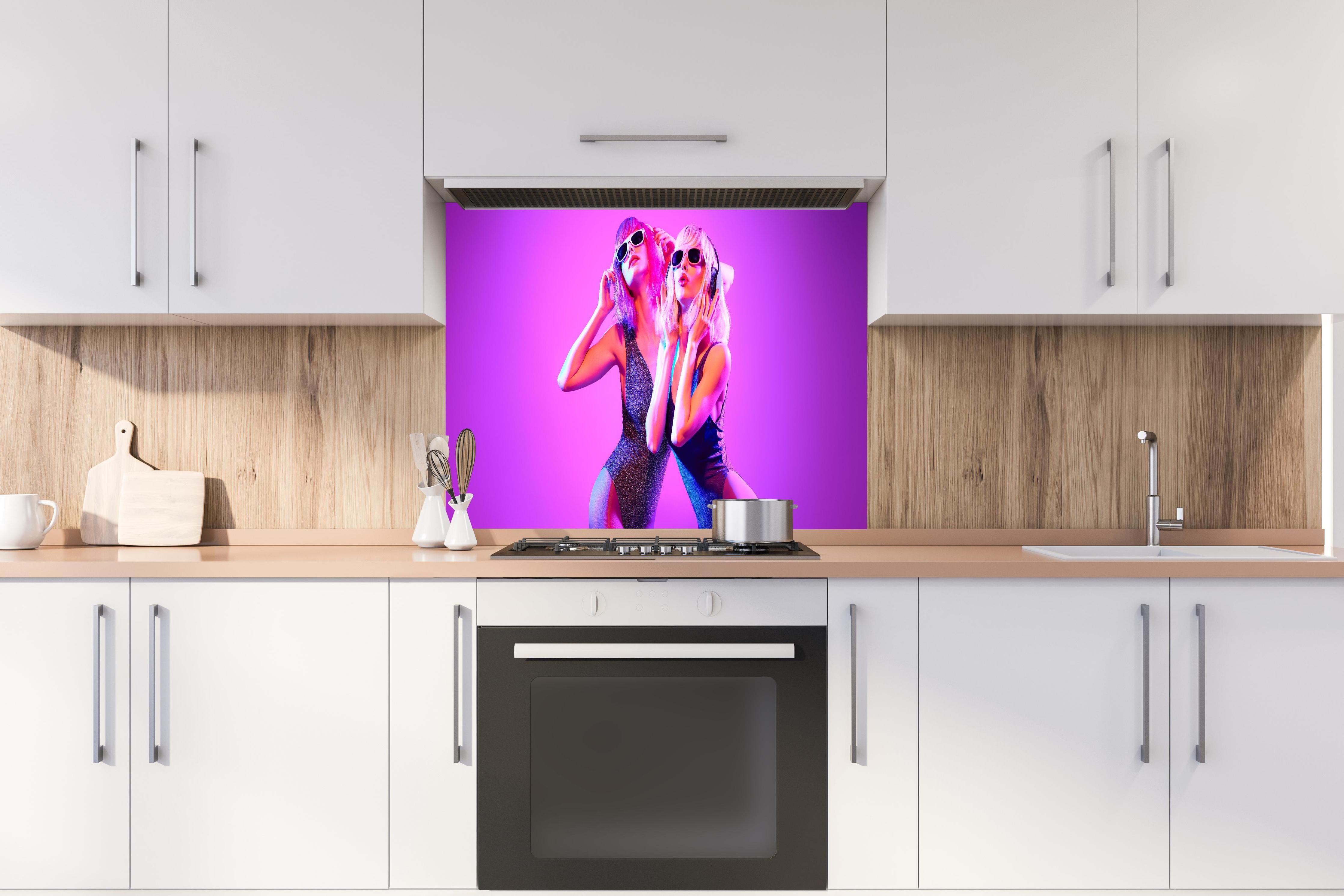 Spritzschutz - Zwei DJ Fitness Frau in bunten Neonlicht. Disco hinter einem Cerankochfeld zwischen Holz-Kochutensilien
