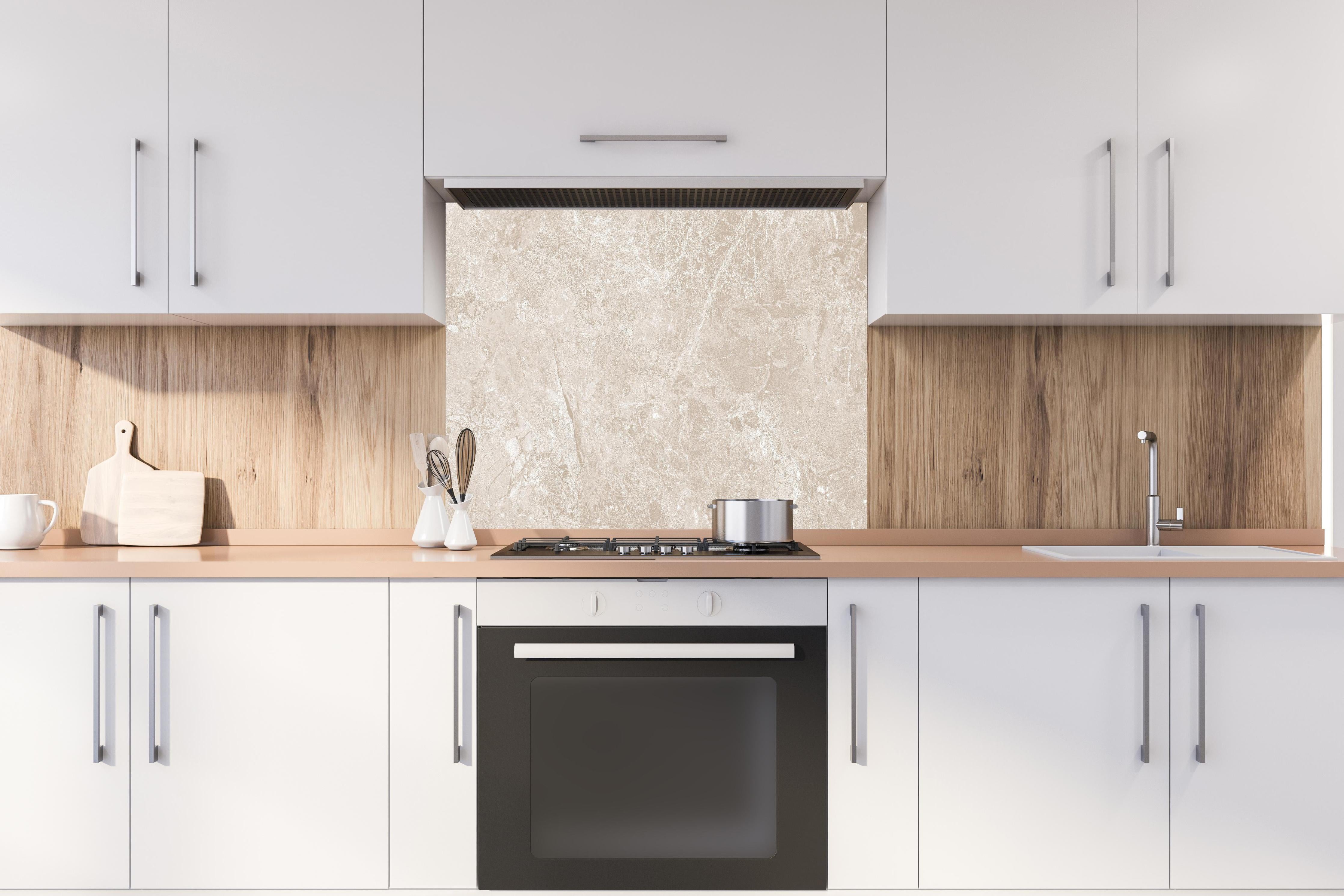 Spritzschutz - beiger Naturmarmor  hinter einem Cerankochfeld zwischen Holz-Kochutensilien
