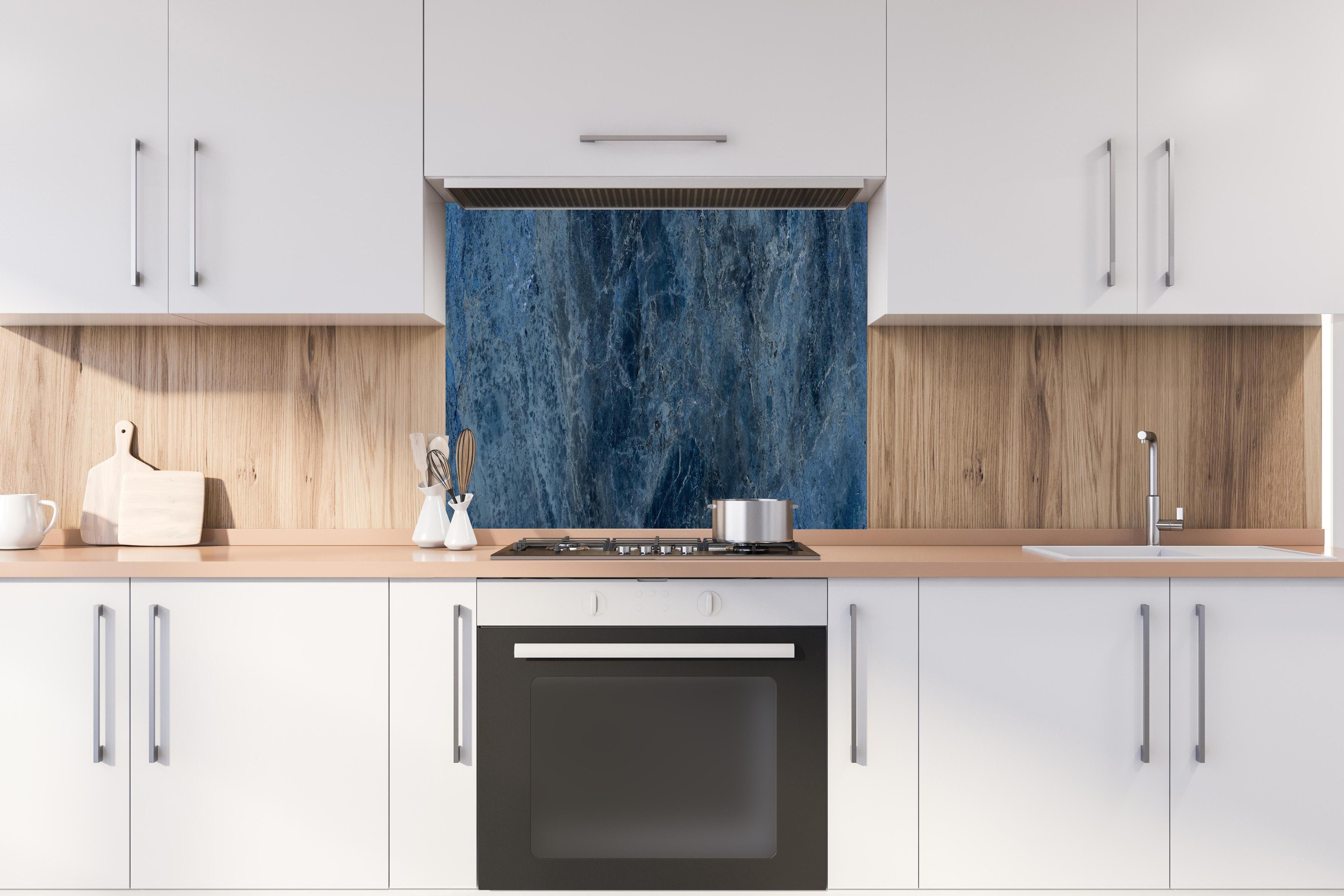 Spritzschutz - dunkelblaue Marmor Steinstruktur hinter einem Cerankochfeld zwischen Holz-Kochutensilien
