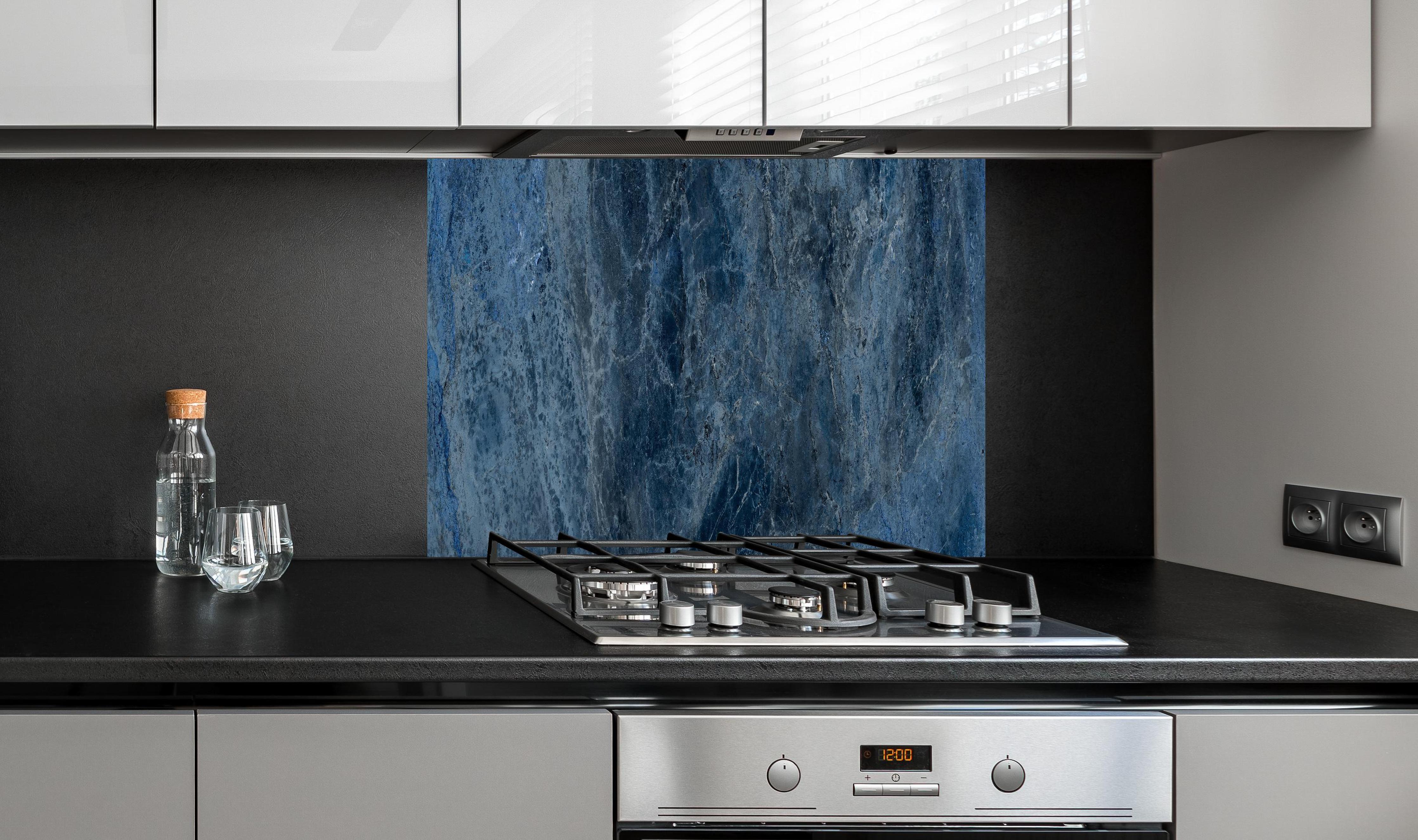 Spritzschutz - dunkelblaue Marmor Steinstruktur hinter einem Cerankochfeld zwischen Holz-Kochutensilien
