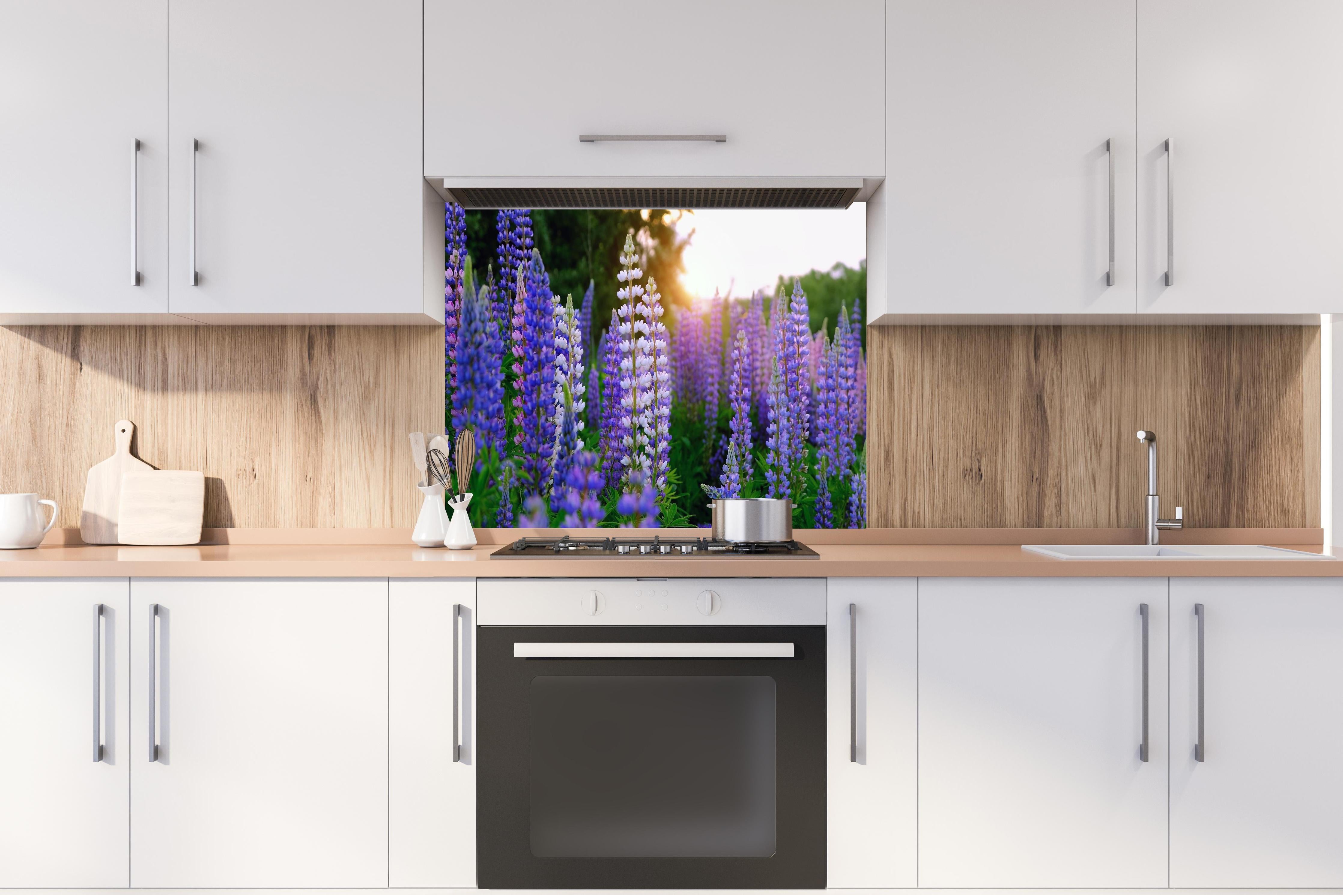 Spritzschutz - lila-rosa Lupine Blumen  hinter einem Cerankochfeld zwischen Holz-Kochutensilien

