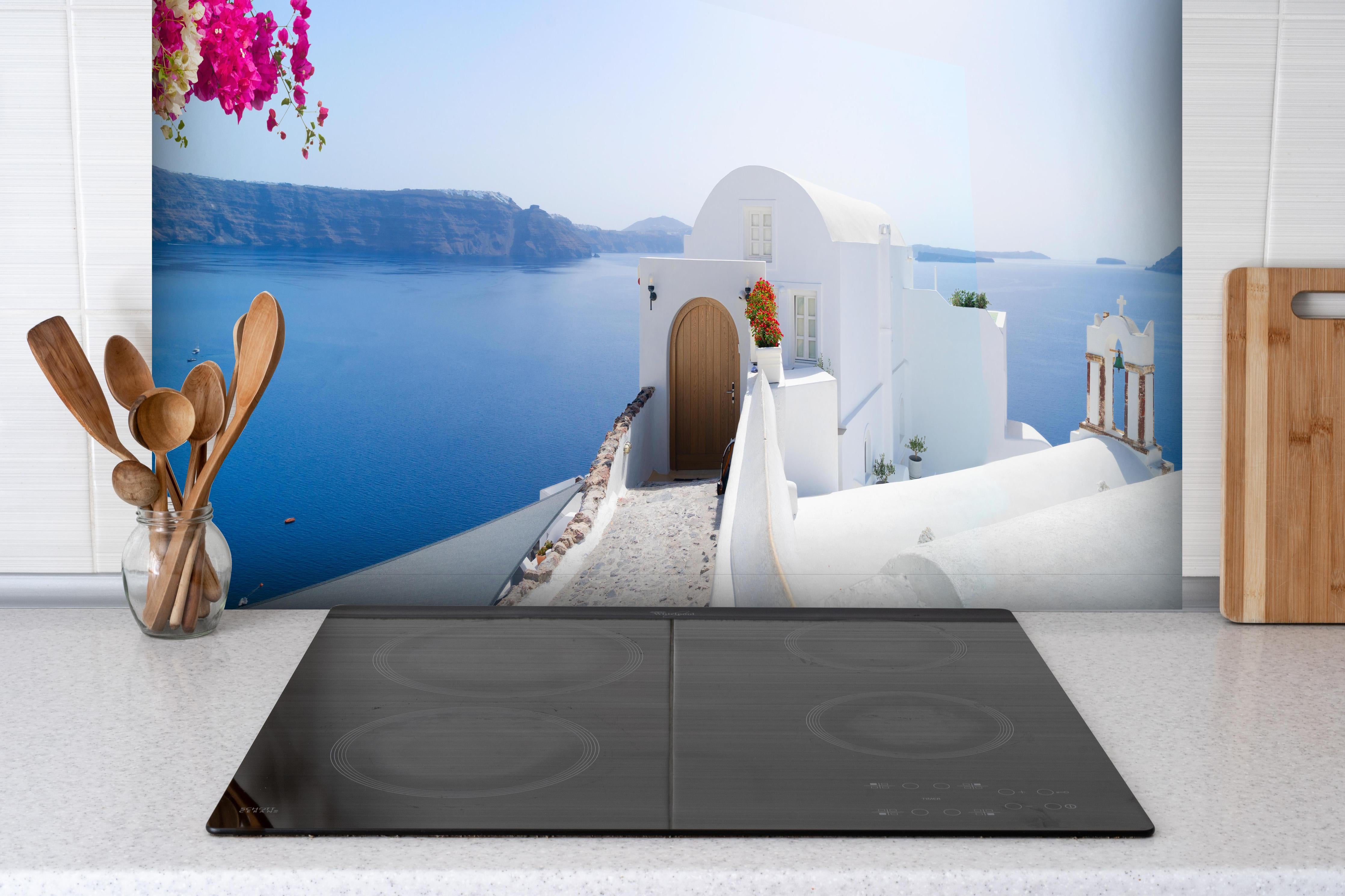 Spritzschutz - schöne Details der Insel Santorin hinter einem Cerankochfeld zwischen Holz-Kochutensilien
