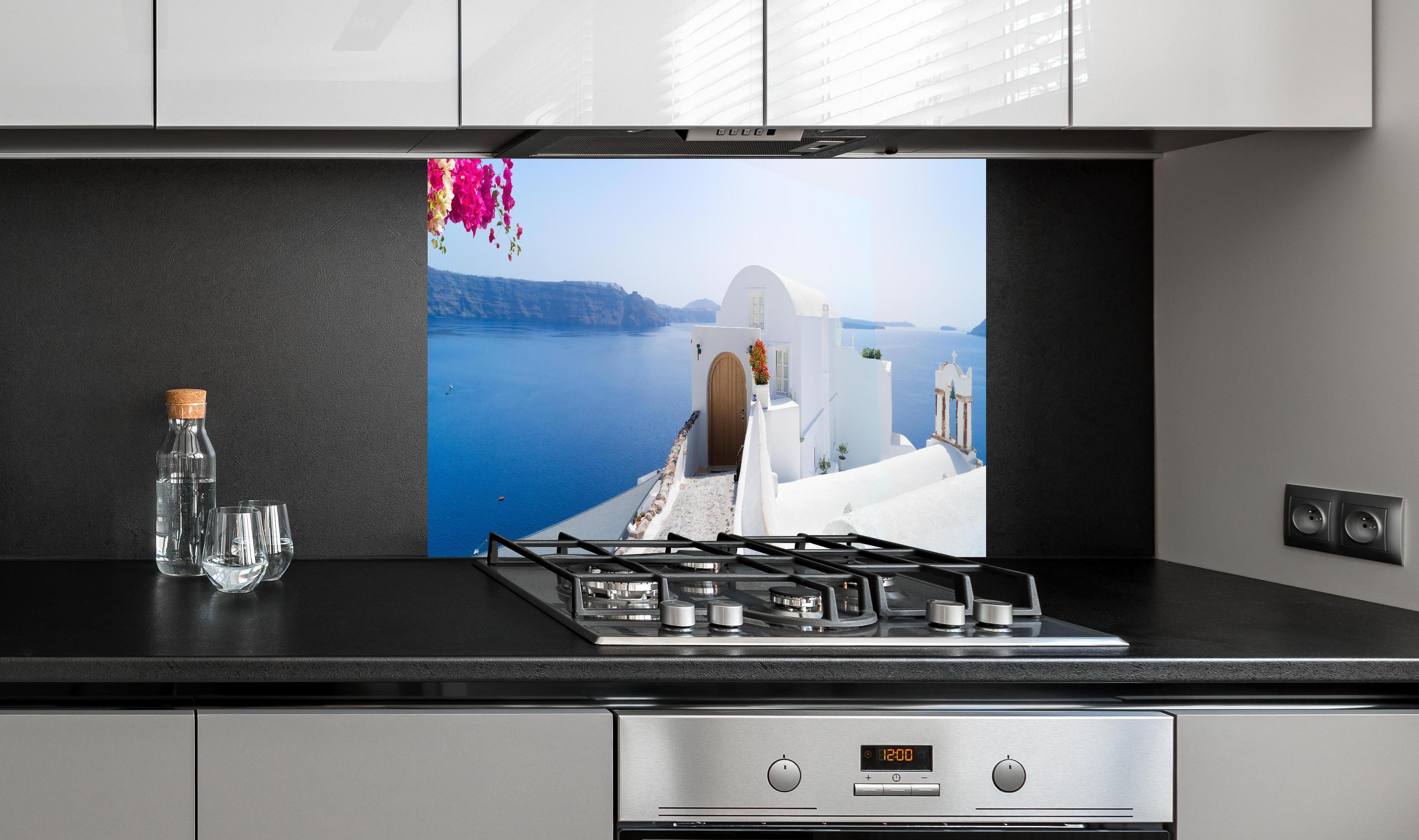 Spritzschutz - schöne Details der Insel Santorin hinter einem Cerankochfeld zwischen Holz-Kochutensilien
