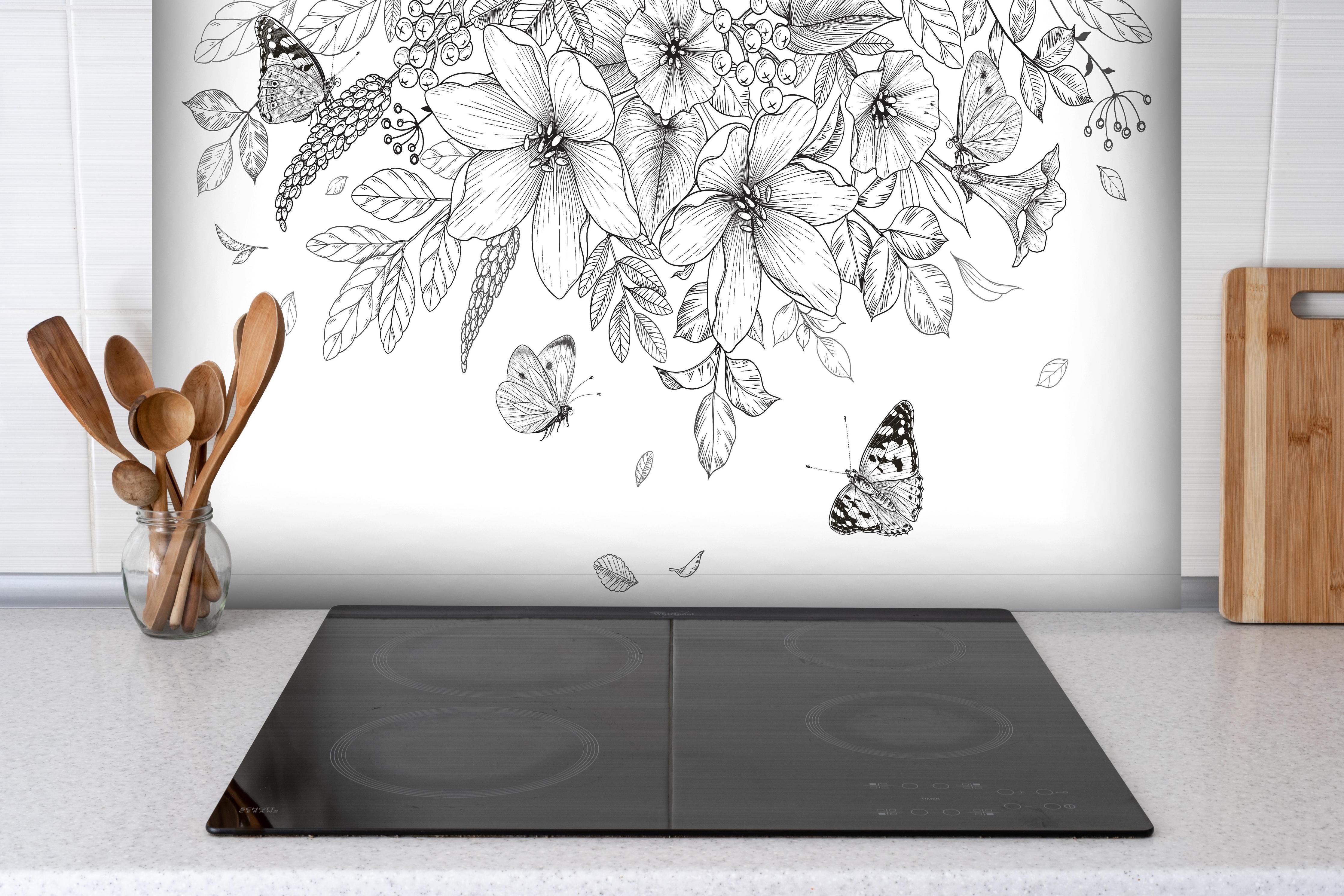Spritzschutz - Florales Muster mit Schmetterlingen S/W hinter einem Cerankochfeld zwischen Holz-Kochutensilien
