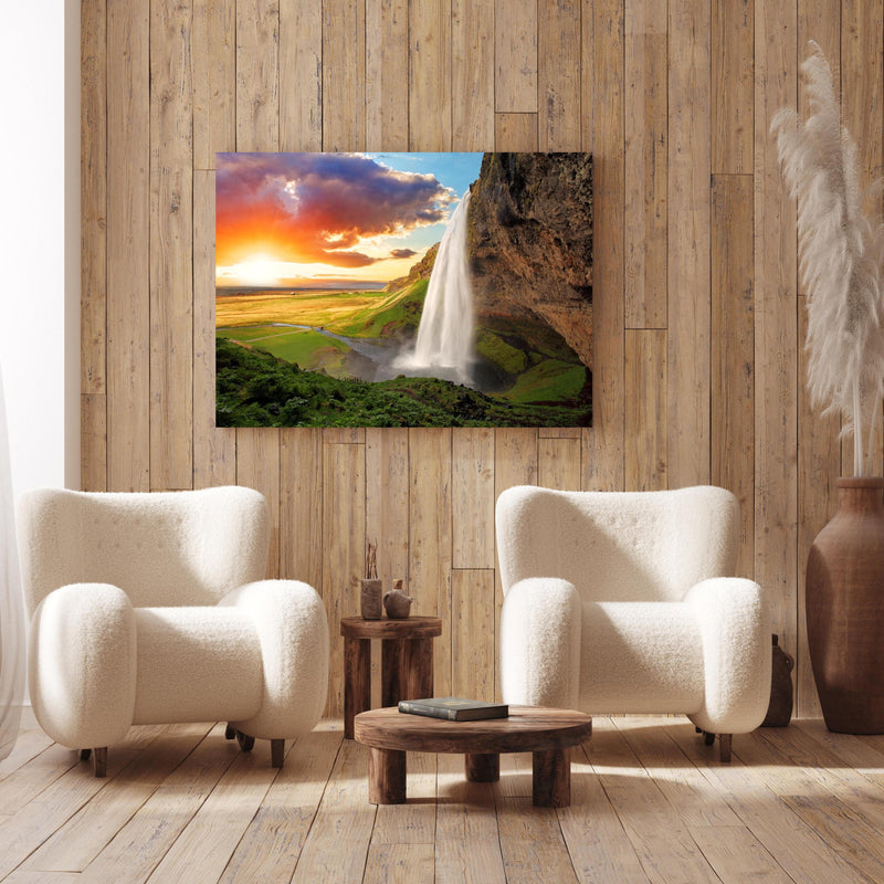 Wandbild -  Seljalandsfoss Wasserfall bei Sonnenuntergang an Holzwand hinter sanften Sesseln mit Plüschbezug