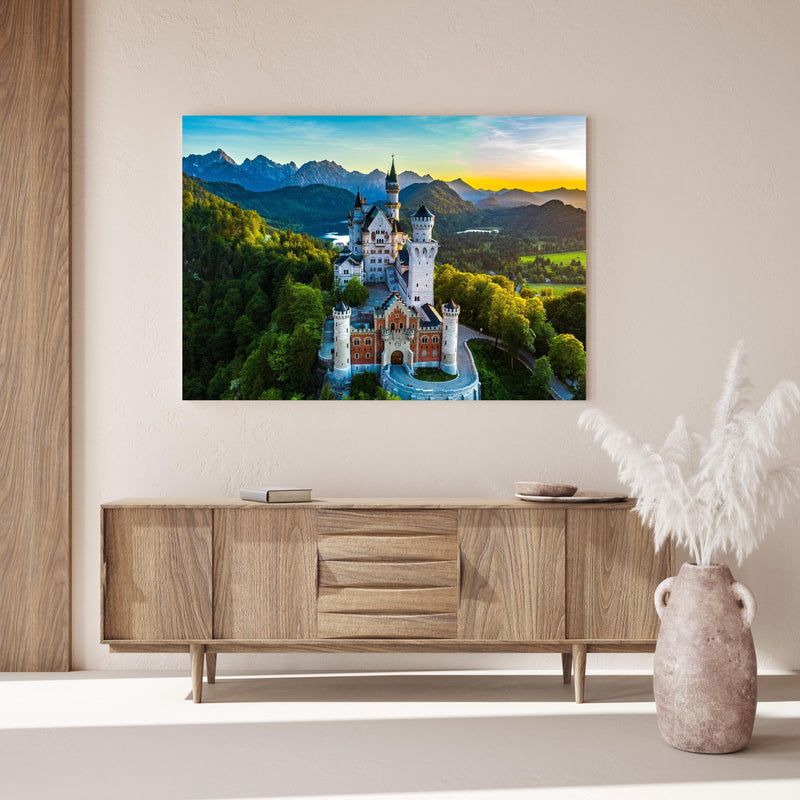 Wandbild -  glanzvolles Märchenschloss Neuschwanstein über Holzkommode hinter dekorativer Zimmerpflanze