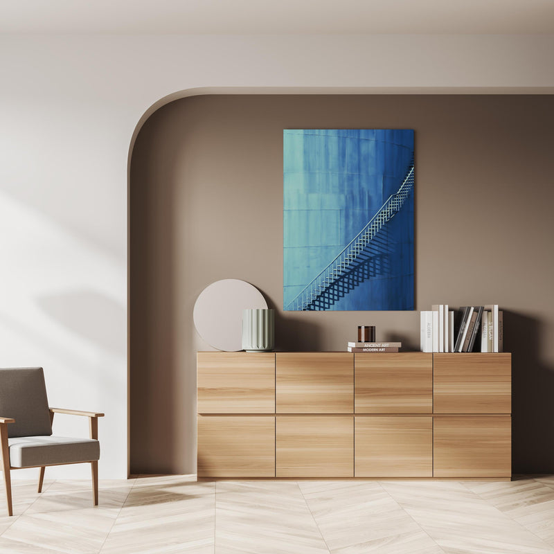 Wandbild - Bläuliche Architektur - Treppen über doppelter Holzkommode mit Vase und Büchersammlung