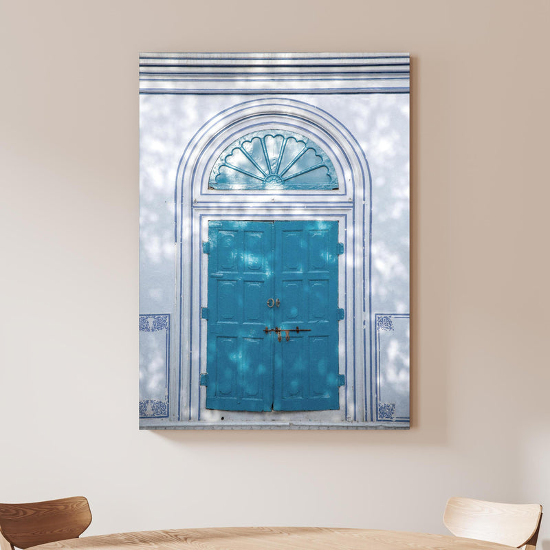 Wandbild - Blaue Tür - Architektur an beiger Wand hinter handgeschnitztem Holztisch Zoom