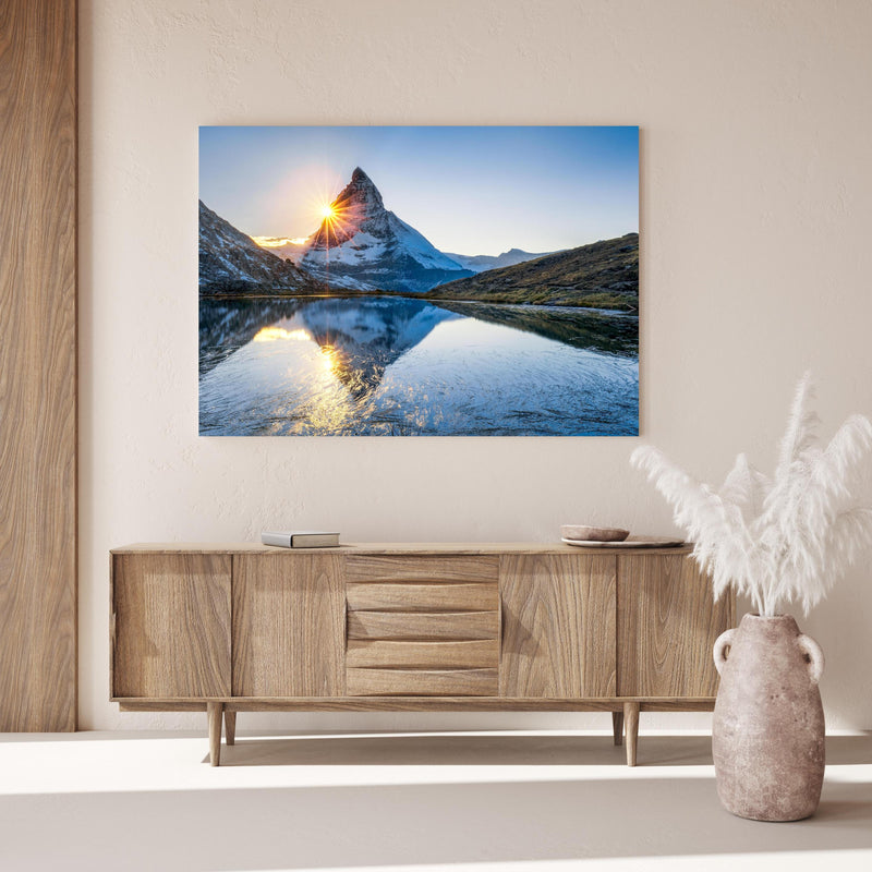 Wandbild - Riffelsee und Matterhorn in den Alpen über Holzkommode hinter dekorativer Zimmerpflanze