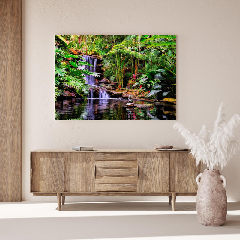 Wandbild - Tropischer Wasserfall über Holzkommode hinter dekorativer Zimmerpflanze