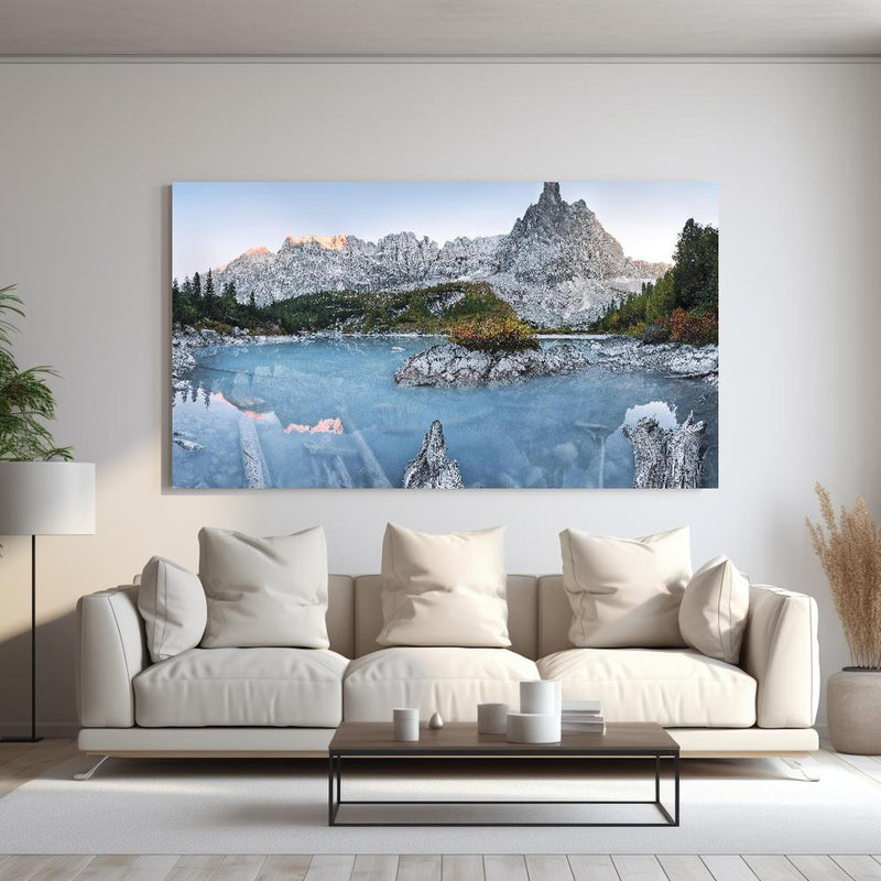 Wandbild - Weiße Berge hinter blauer Wasserlandschaft hinter sanfter Couch mit cremefarbenen großen Kissen