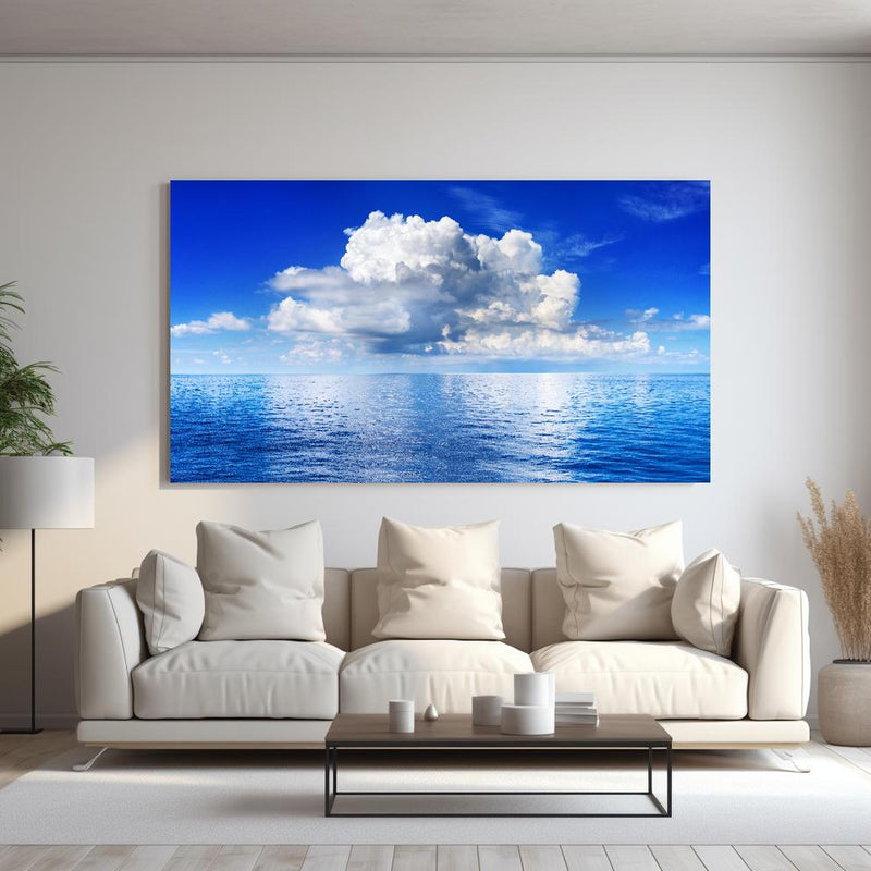 Wandbild - Wolkenkulisse über dem Ozean hinter sanfter Couch mit cremefarbenen großen Kissen