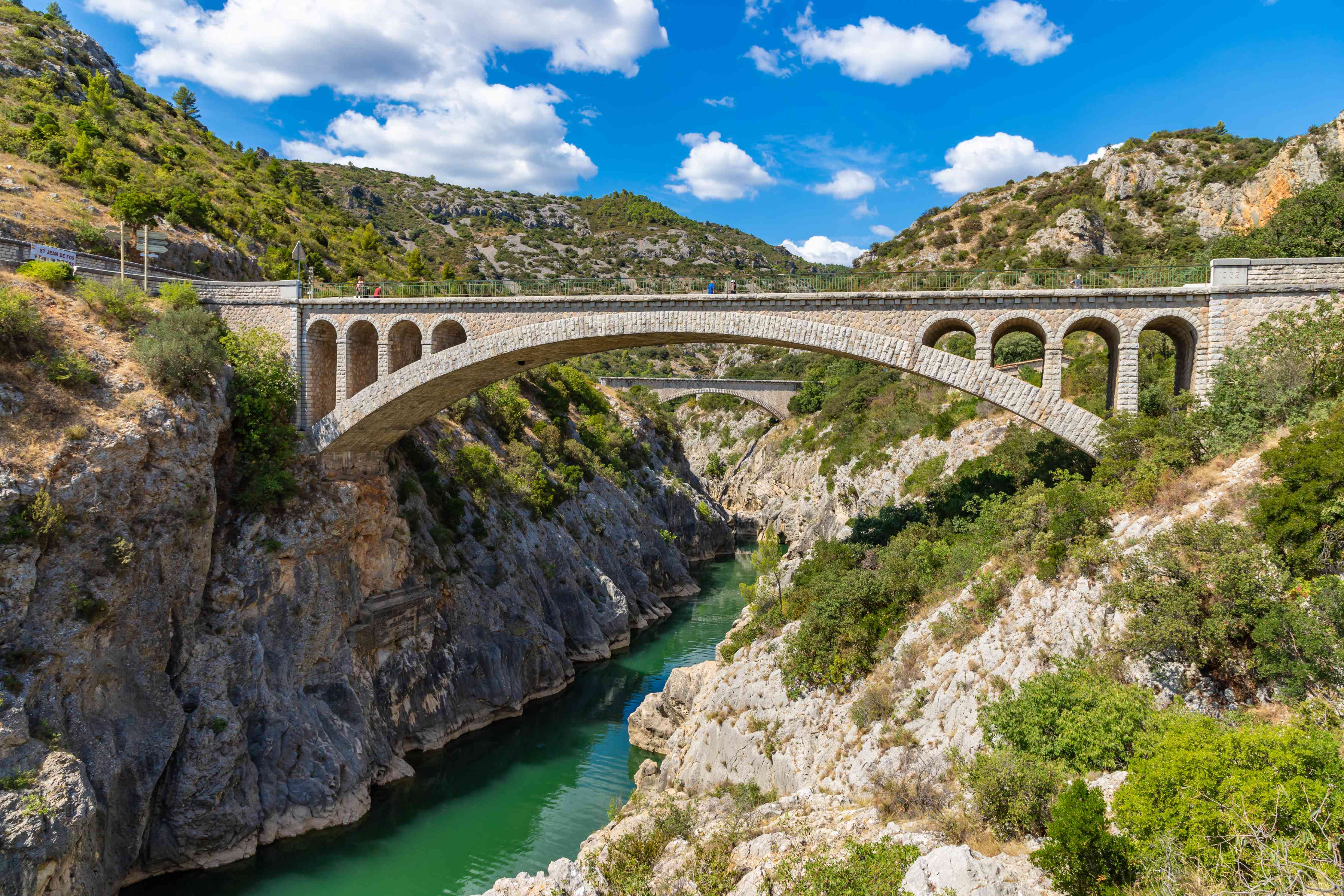 Wandverkleidung Wohnzimmer-Historische Steinbrücke über Fluss inmitten der Natur