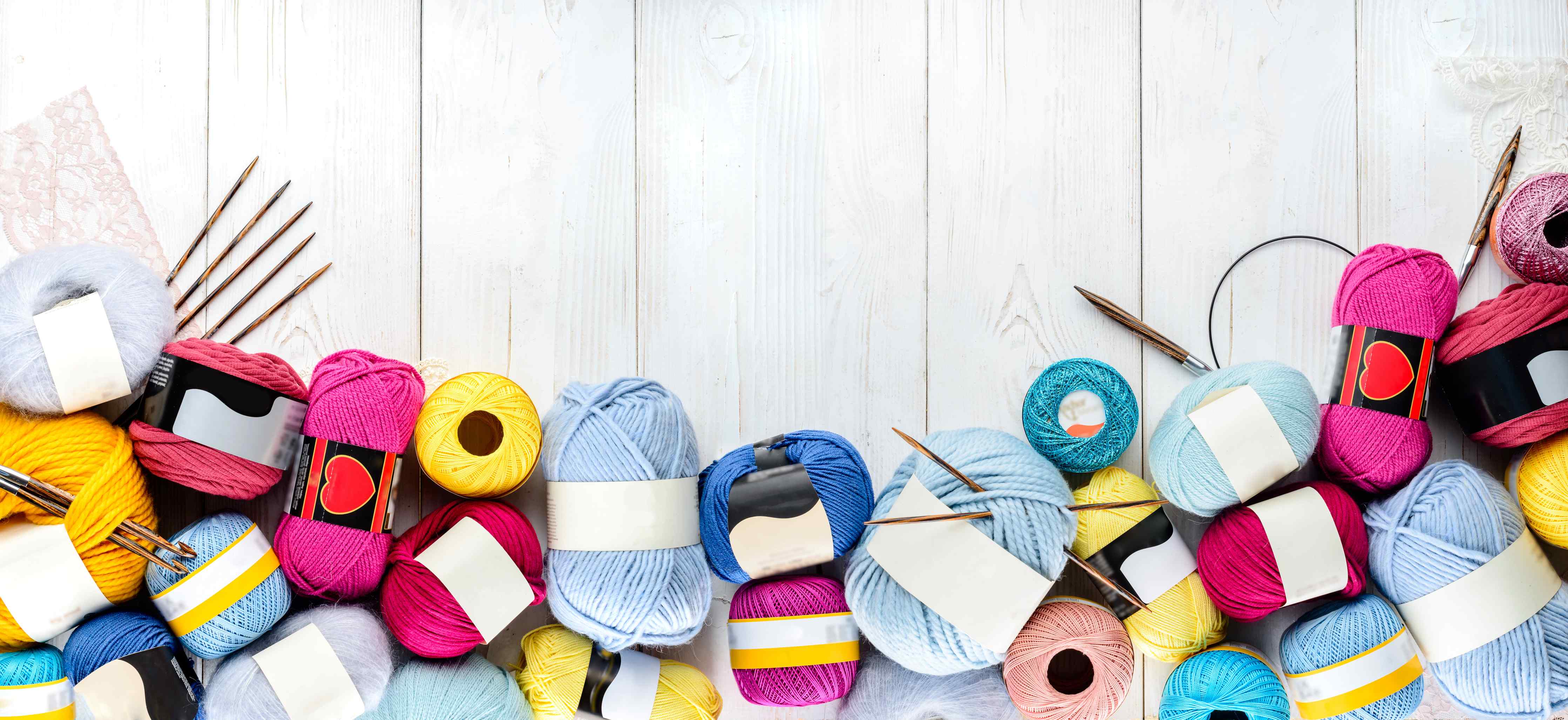 Wandverkleidung Wohnzimmer-Wolle und Stricknadeln auf Holzhintergrund