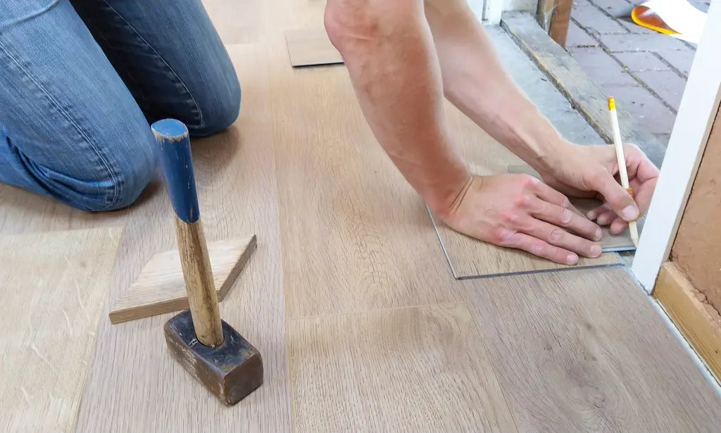 Handwerker misst und markiert bei der Bodenmontage